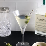 a dry gin martini in a glass with a skewer of olives.