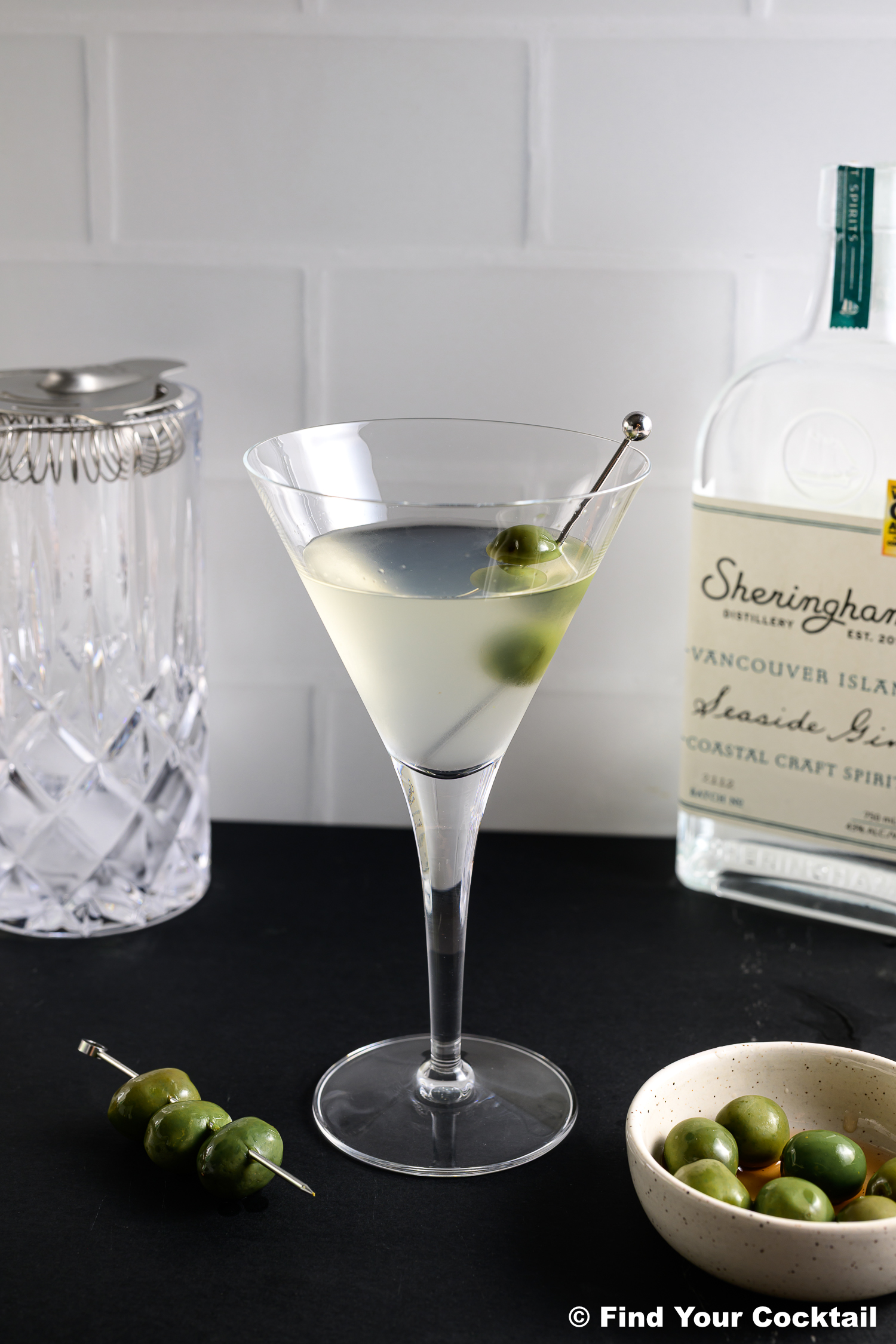 a dry gin martini in a glass with a skewer of olives. 