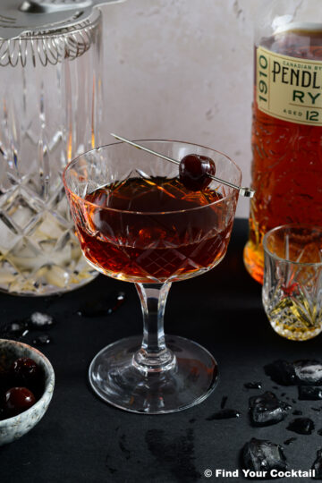 A Manhattan in a coupe glass with a brandy cherry garnish