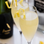 Two French 75 cocktails in champagne flutes garnished with lemon twists.