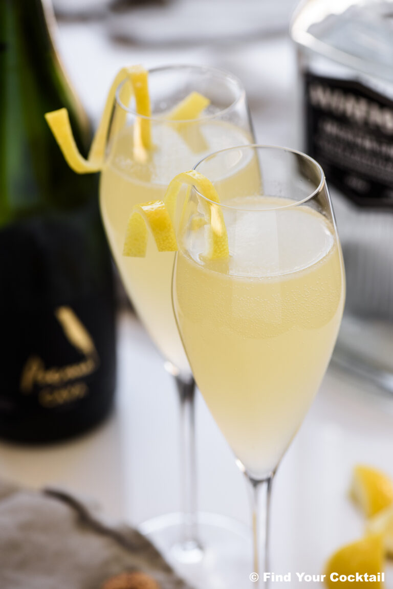 Two French 75 cocktails in champagne flutes garnished with lemon twists.