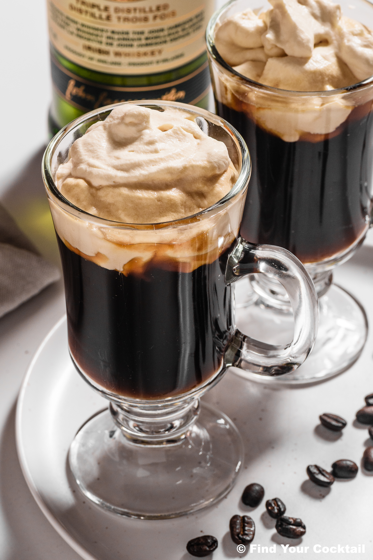 A tall mug of Irish coffee topped with whipped cream