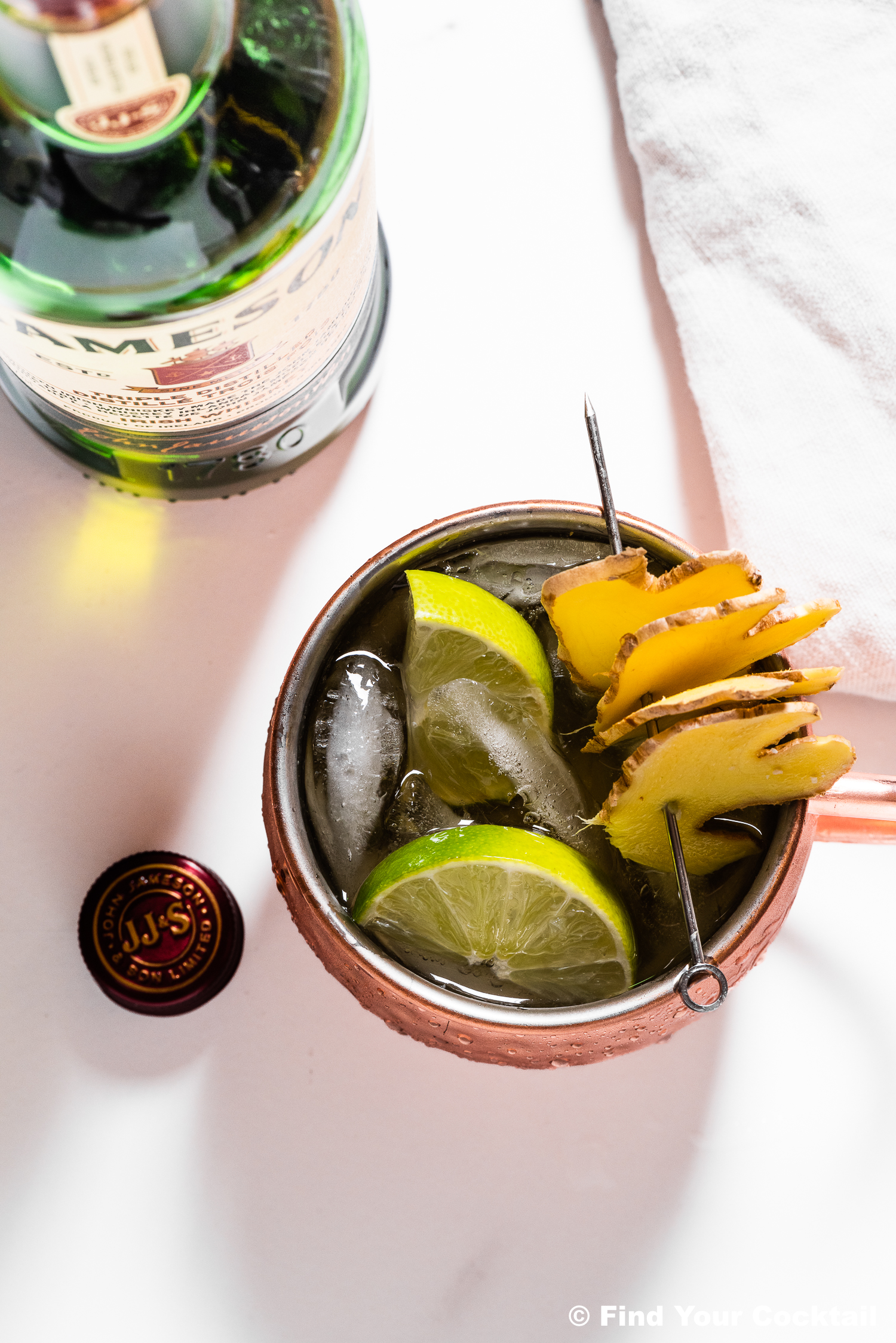 Looking down on a drink in a copper mule mug with a bottle of Irish whiskey in the back