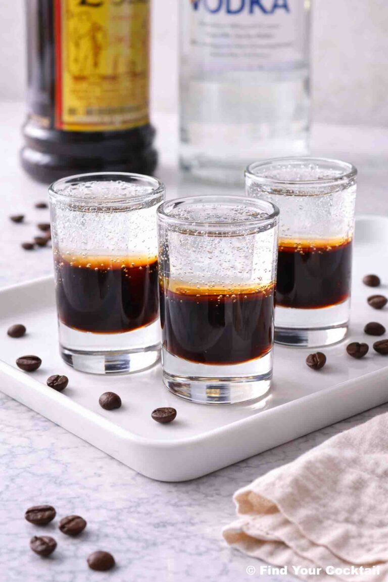 three mind eraser shots on a white tray with bottles of alcohol in the background