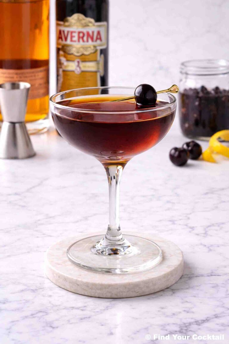 a lack manhattan in a coupe glass with a bottle of Averna in the background