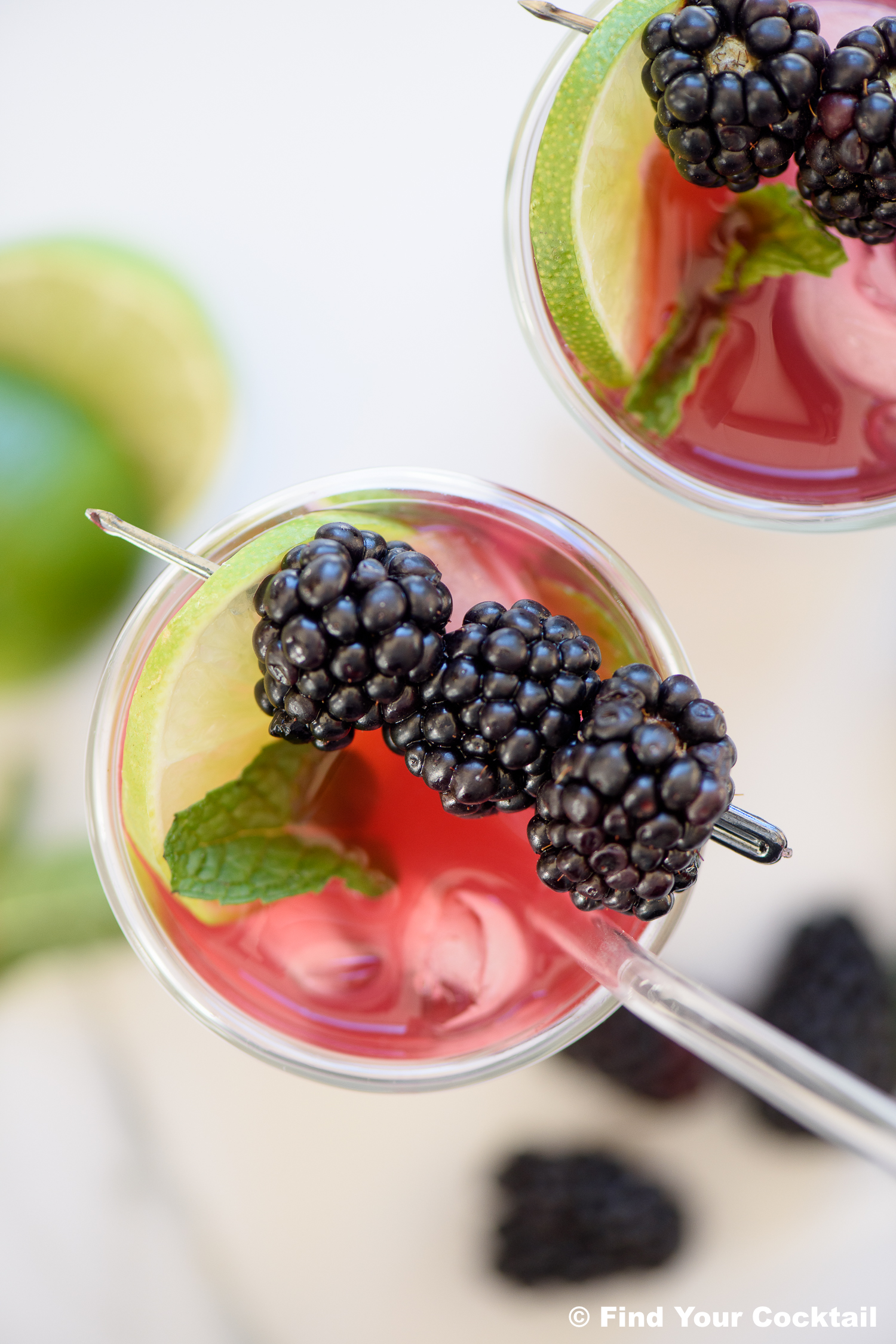 looking down on a blackberry mojito with a glass straw