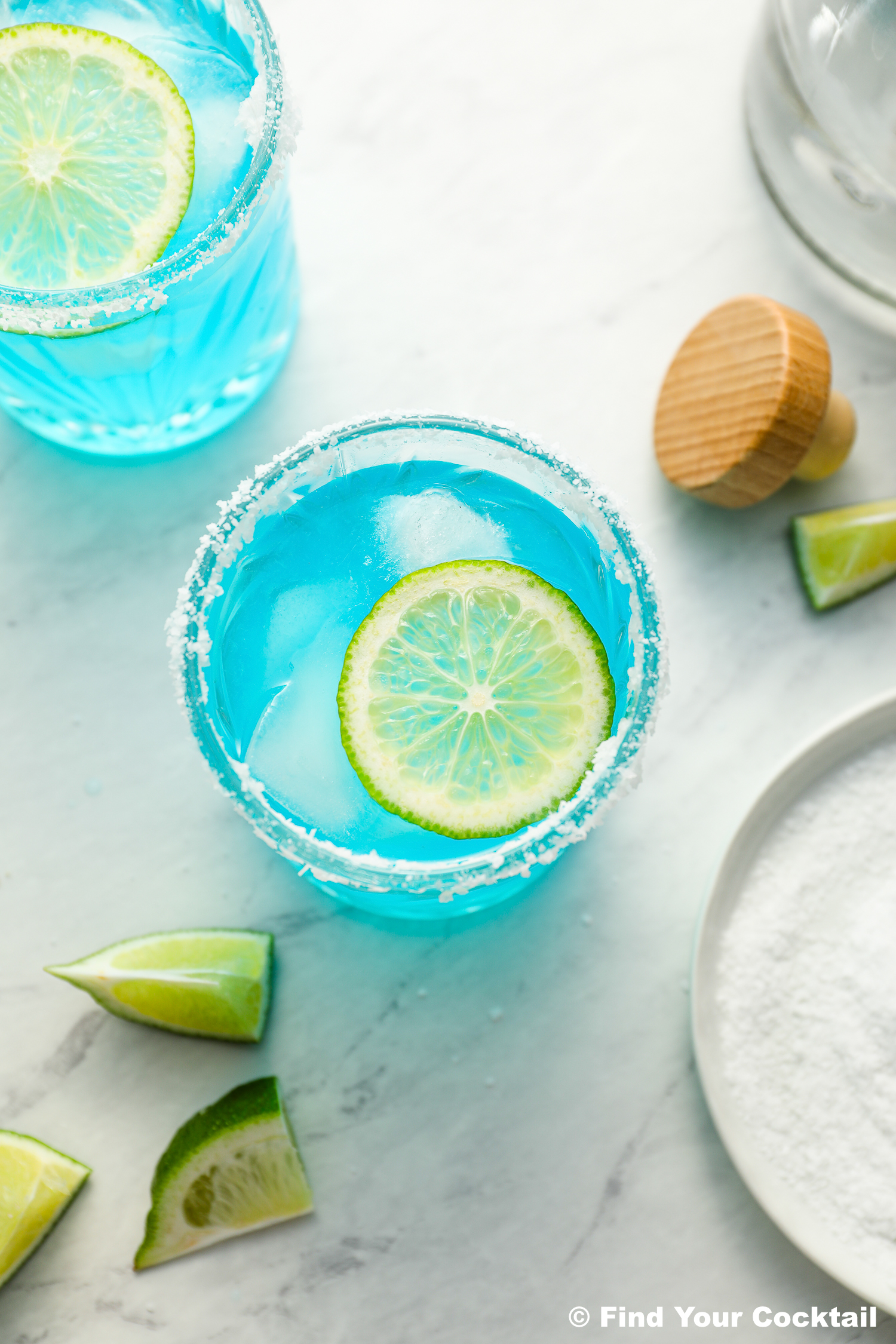 a blue margarita with a bottle of tequila on the side.