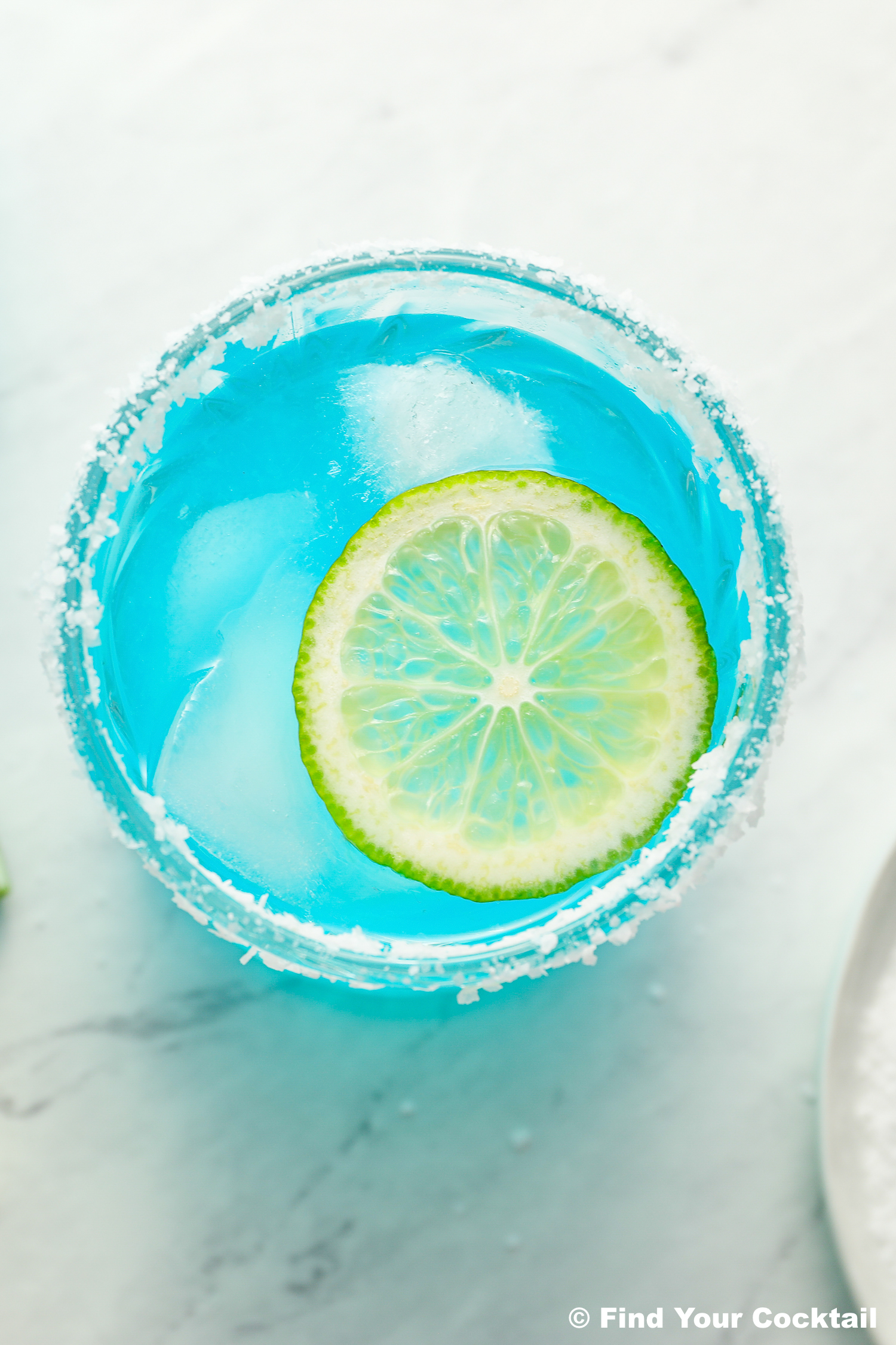 looking down on a glass of blue margarita with a lime wheel on top
