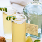 two champagne margaritas next to a bottle of tequila