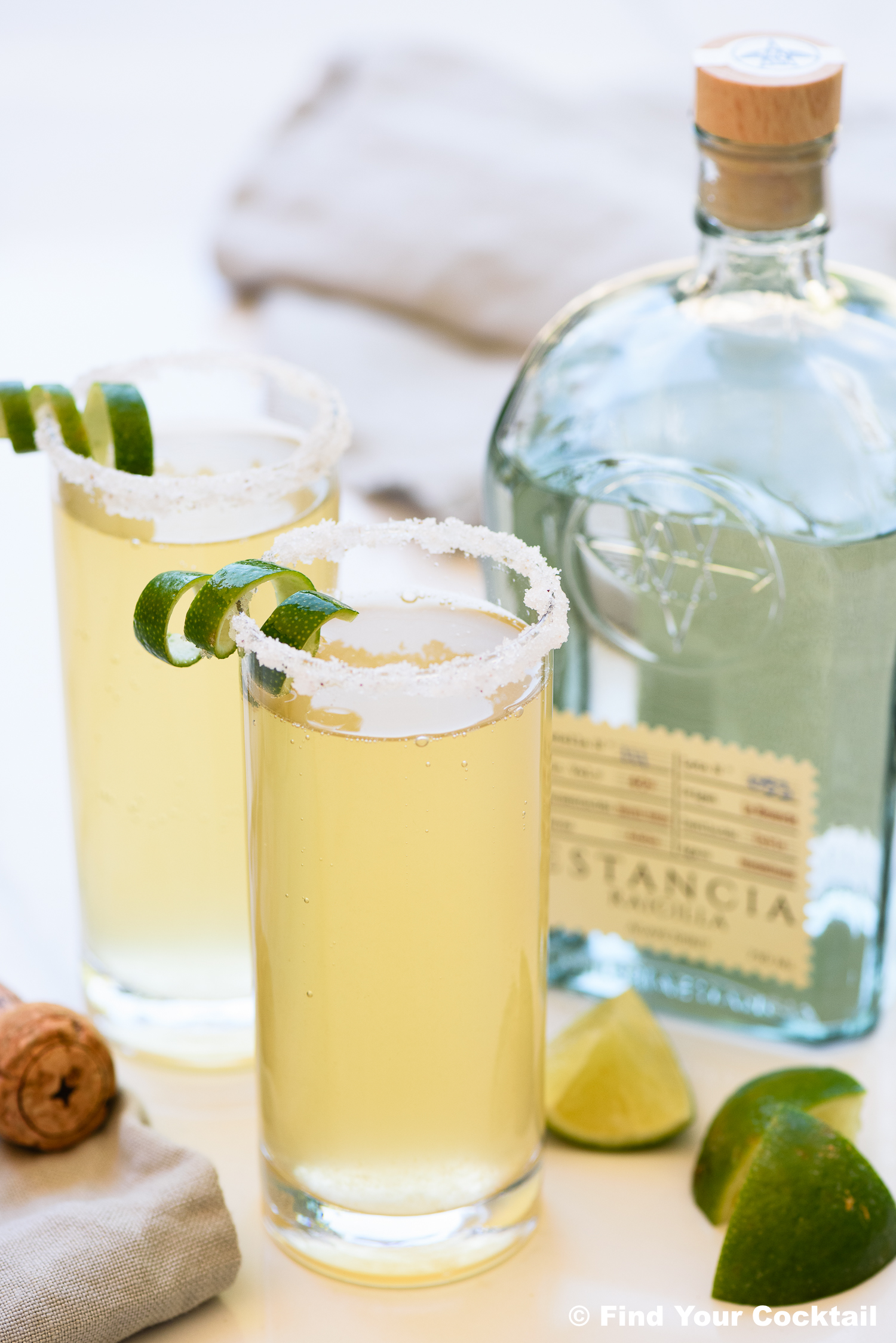 two champagne margaritas next to a bottle of tequila