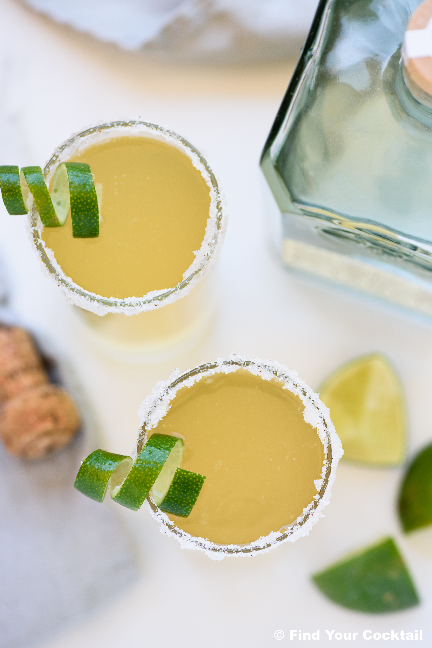 looking down on two mexican 75 cocktails garnished with lime twists