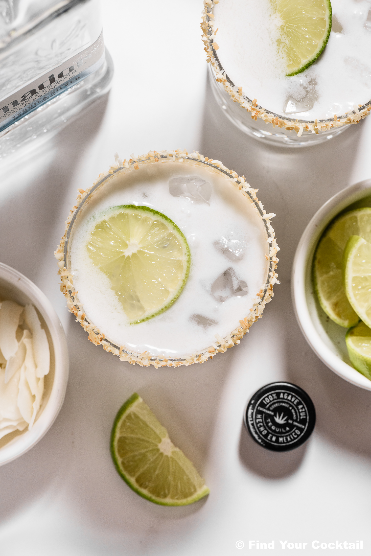 coconut margaritas with toasted coconut rim surrounded by limes.