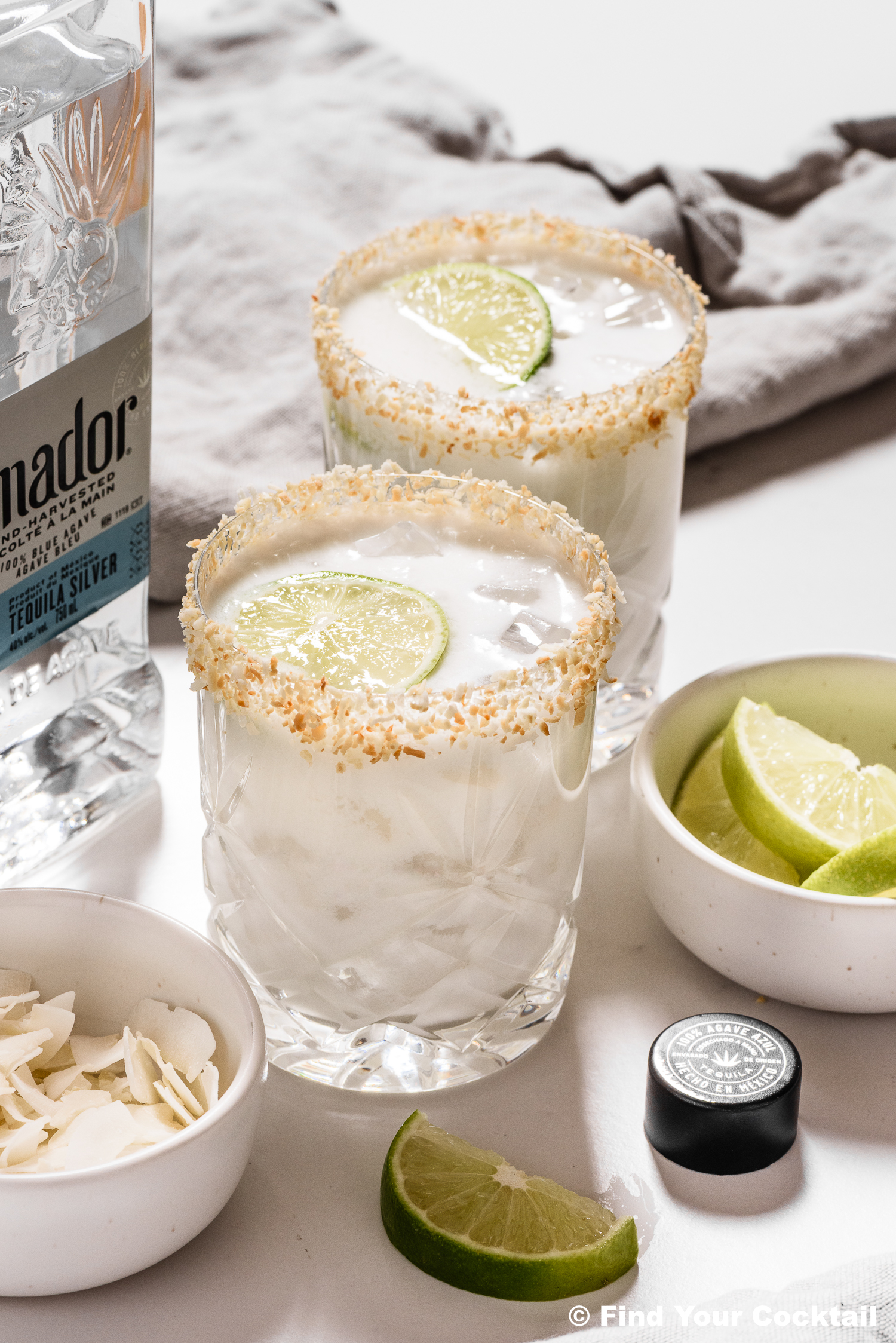 2 coconut margaritas next to a bottle of tequila