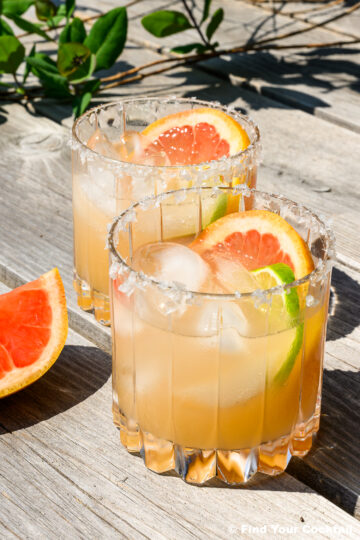 2 grapefruit margaritas on a table outside in the sun