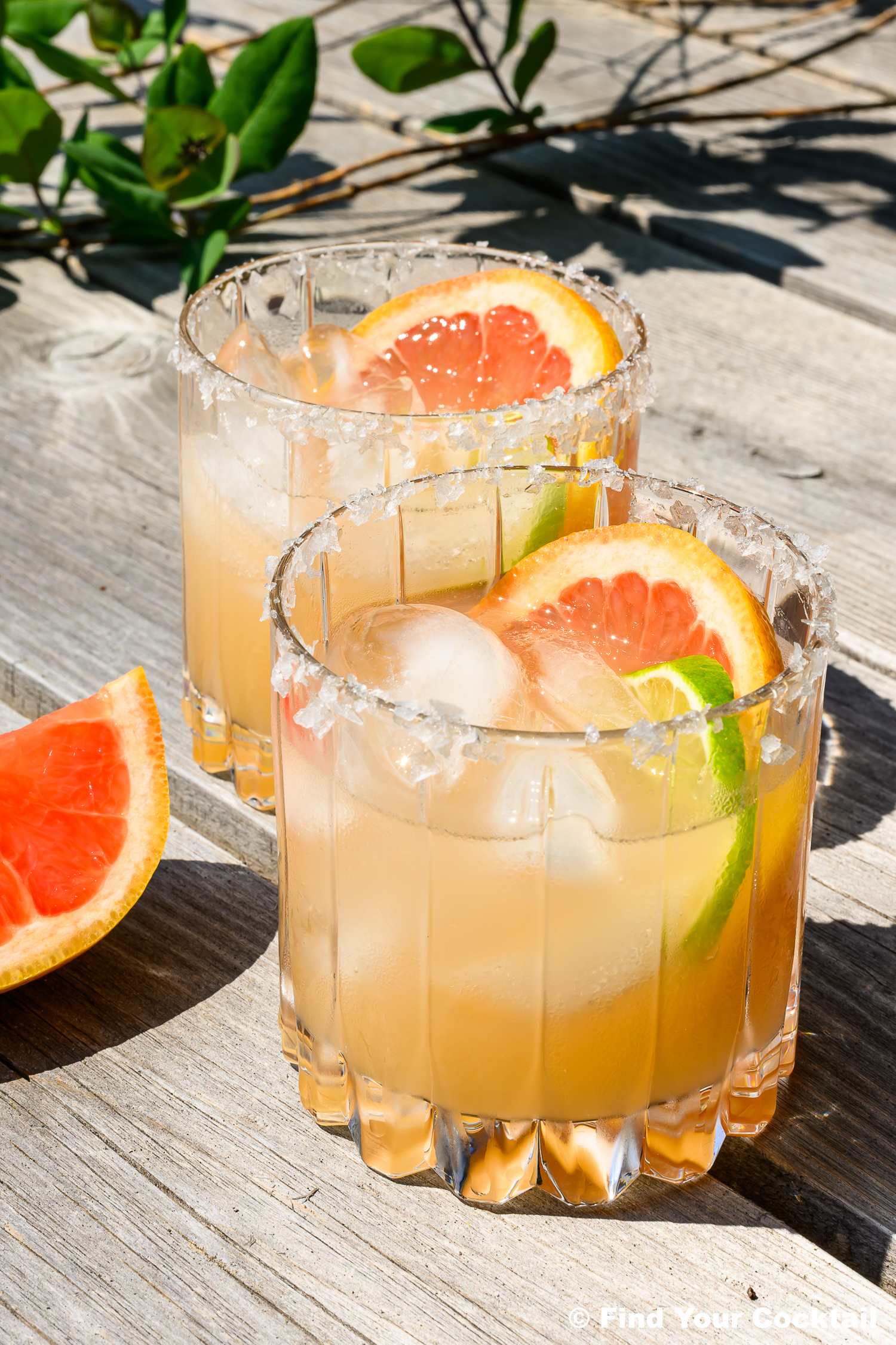2 grapefruit margaritas on a table outside in the sun