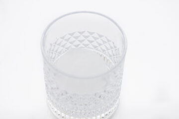 Clear, empty glass tumbler with a diamond-patterned texture, viewed from above against a plain white background.