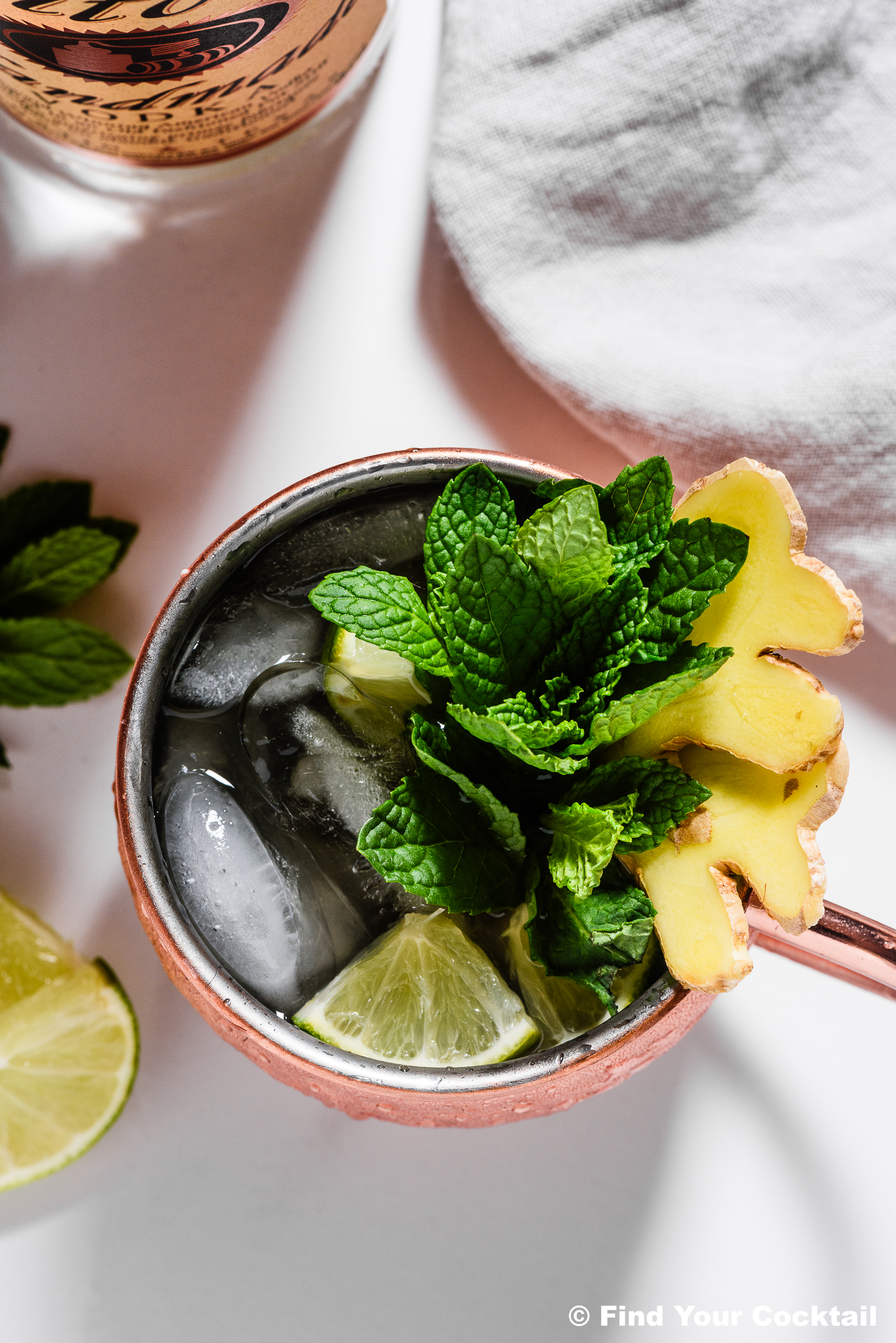 looking down on a moscow mule in a copper mug garnished with lots of mint and some sliced ginger