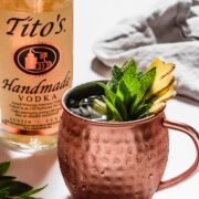 a moscow mule in a classic copper mug next to a bottle of vodka