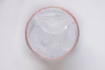 Top-down view of a cup filled with ice cubes, with a pinkish rim visible around the edge of the cup.