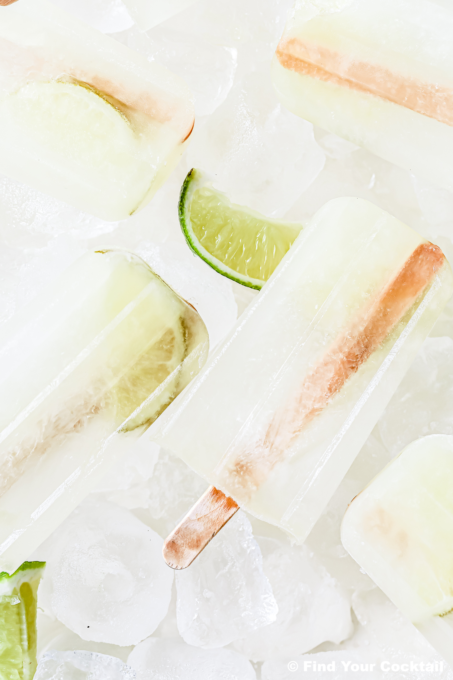Several clear popsicles with lime wedges are arranged on ice.
