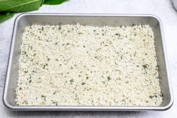 A metal baking pan filled with an even layer of salt mixed with chopped sage.